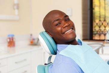 man sitting in dental exam chair | dental exams harrisonburg